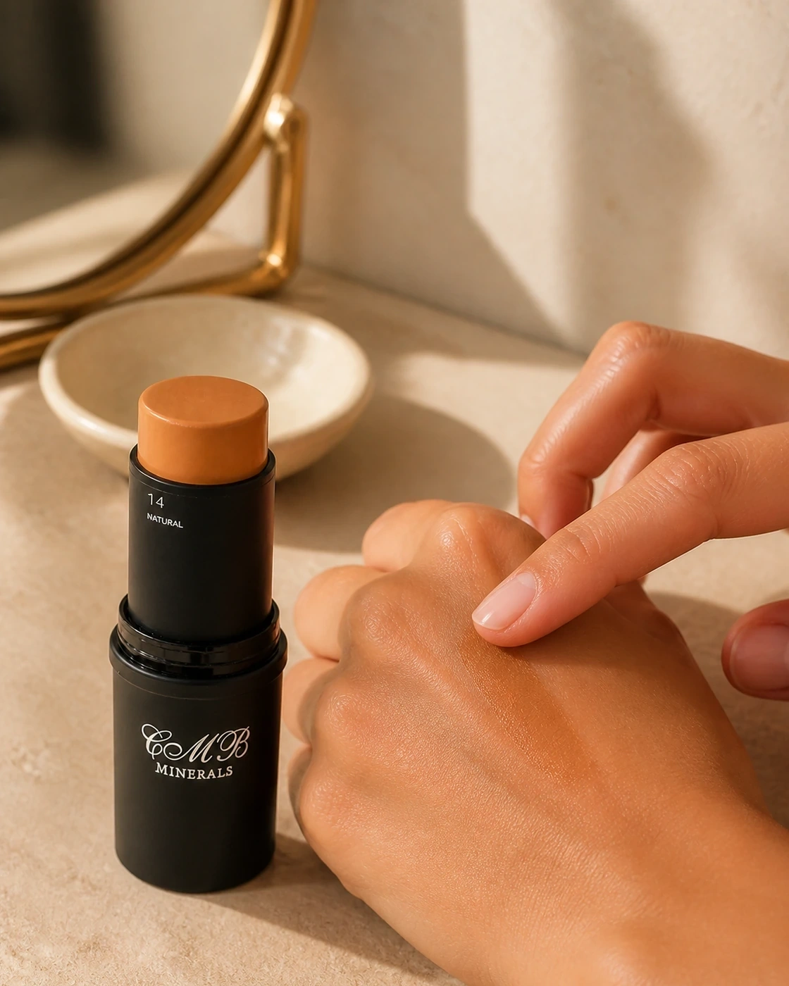 Maquillaje en crema Natural junto a un swatch sobre la mano en un tocador con espejo